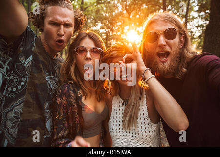 Foto di allegro hippies uomini e donne sorridenti e tenendo selfie nella foresta Foto Stock