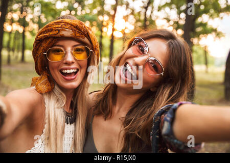 Foto di due gioiosa hippie donna sorridente e tenendo selfie mentre  passeggiate in foresta Foto stock - Alamy