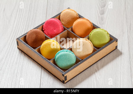 Amaretti gustosi dolci di diverso colore marrone in una scatola di legno su schede di colore grigio Foto Stock