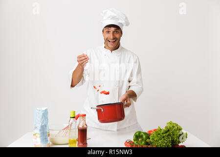 Immagine del bel giovane chef uomo isolato oltre il muro bianco sullo sfondo di cottura. Foto Stock