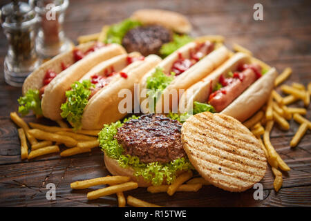 Hot Dog, Hamburger e patatine fritte. Composizione del fast food snack. Posto su rusty tavolo in legno. Vista dall'alto. Foto Stock