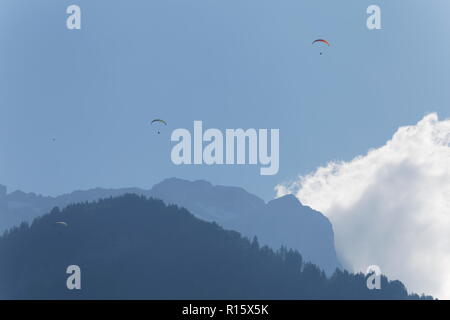 Parapendio in volo la mattina presto nebbie in tra le montagne sopra il lago di Annecy Francia Foto Stock
