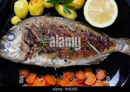 Uno squisito pasto sano: orata, rosolate le carote e le patate al forno Foto Stock