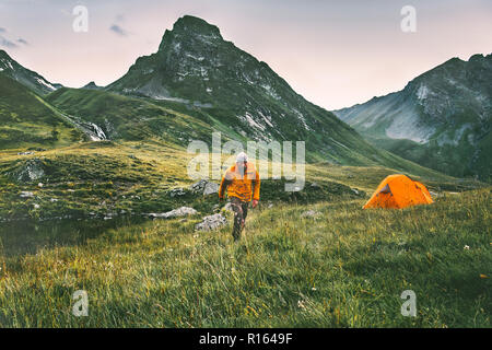 L'uomo escursionismo da soli solo campeggio viaggio avventura il concetto di stile di vita attivo vacanze estive con la tenda in montagna Foto Stock