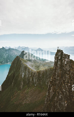 Uomo di arrampicata in Norvegia traveler permanente sulla scogliera Rocky Mountain avventura estrema lifestyle vacanze vista aerea paesaggio Foto Stock
