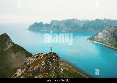 Norvegia vacanze donna in piedi da sola sulla scogliera di montagna sopra bordo mare viaggi avventura outdoor lifestyle Senja paesaggio delle isole Foto Stock