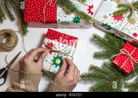 Mani femminili di incarto scatola regalo su sfondo bianco con brunch e doni. Natale e Anno Nuovo sfondo vacanze Foto Stock