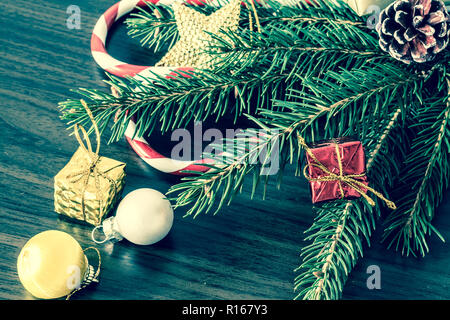 Il ramo di un albero di Natale con le palle, abete coni, caramelle tradizionali e scatole con doni sulla botte backgroun.Natale e Anno Nuovo sfondo. Vint Foto Stock