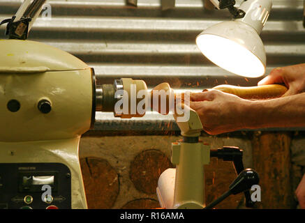 Chiudere fino alle mani di un maestro maschio woodturner tornitura di una ciotola di legno su un tornio Foto Stock