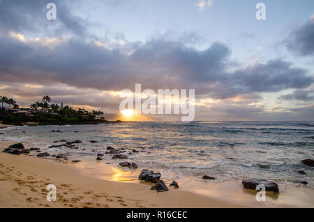 Onde in rotolamento su piccole pietre coralline a Chun Reef e Jocko's Cove su Oahu North Shore in Hawaii in sunset Foto Stock