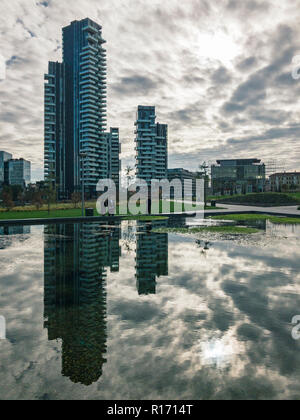 Libreria di alberi, nuova Milano Parco. Solaria torre. Sentieri del Parco con una vista panoramica di grattacieli, Italia. Torre specchiata nella fontana Foto Stock