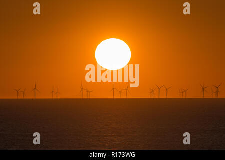 Tramonto sul mare con turbine eoliche all'orizzonte Foto Stock