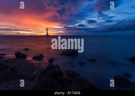 Croce cattolica silhouette in un cimitero affondata al crepuscolo, Camiguin island, Filippine Foto Stock