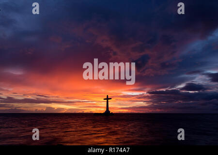 Croce cattolica silhouette in un cimitero affondata al crepuscolo, Camiguin island, Filippine Foto Stock