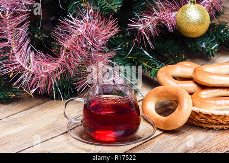 Il tè caldo e ciambelle su una tavola di legno sotto l'albero di Natale. Stile rustico. Close up. Concetto di natale Foto Stock