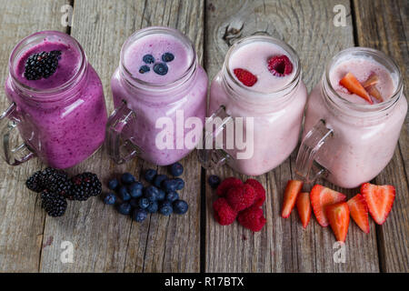 Selezione di coloratissimi detox berry bevande su uno sfondo di legno Foto Stock