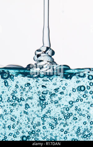 Blu trasparente gel con bolle essendo spruzzata contro uno sfondo bianco Foto Stock
