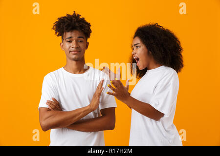 Ritratto di un giovane africano in piedi isolato su sfondo giallo avente un argomento, urlando Foto Stock