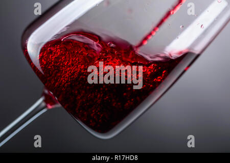 Il vino rosso è versata nel bicchiere di vino. Foto Stock