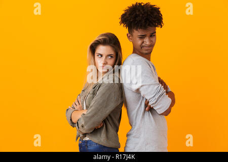 Ritratto di un sconvolto multietnica giovane in piedi isolato su sfondo giallo, dorso a dorso Foto Stock