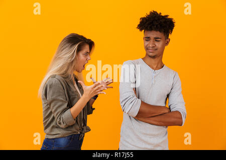 Ritratto di un arrabbiato multietnica giovane in piedi isolato su sfondo giallo avente un argomento Foto Stock