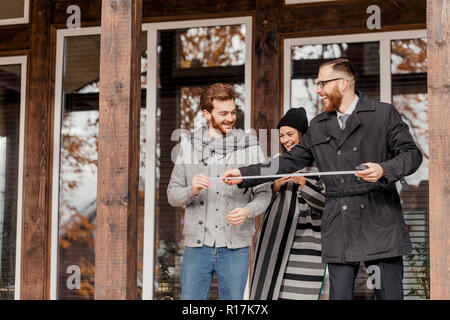 Agente immobiliare e i clienti in piedi accanto a casa Foto Stock