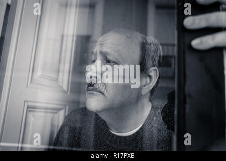 Senior l uomo nella sua 60s sensazione disperata triste guardando tutto il balcone preoccupato premuto riflessivo e solitaria a casa in invecchiamento mentale di depressione Foto Stock