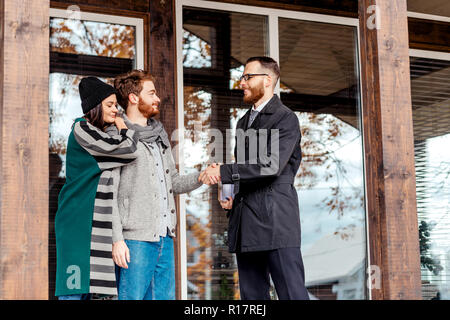 Coppia giovane con agente immobiliare vicino casa, acquisto di beni immobili Foto Stock