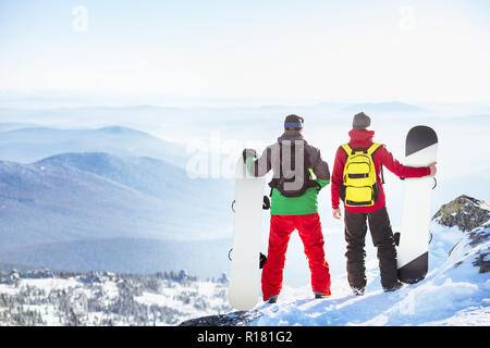 Due gli snowboarder sorge sulla cima della montagna al punto di vista Foto Stock