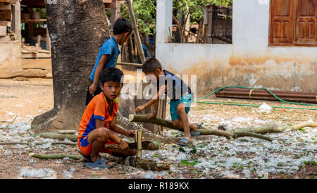 Thakhek, Laos - 21 Aprile 2018: i bambini che lavorano con boschi in un remoto villaggio rurale della provincia Khammouane. Il lavoro minorile è un problema comune nel Foto Stock