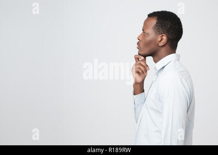 Profilo del giovane africano concentrando avente un pensiero. Provare a risolvere i problemi di finanziamento. Foto Stock