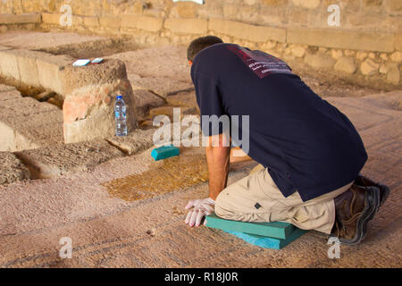 4 Maggio 2018 alcuni dei lavori di restauro al 1 ° secolo sinagoga nel borgo antico di Magdala in Galilea, Israele. Un commerciante continua a d Foto Stock