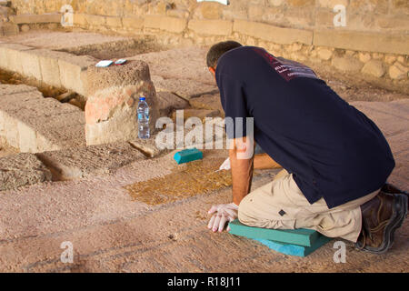 4 Maggio 2018 alcuni dei lavori di restauro al 1 ° secolo sinagoga nel borgo antico di Magdala in Galilea, Israele. Un commerciante continua a d Foto Stock