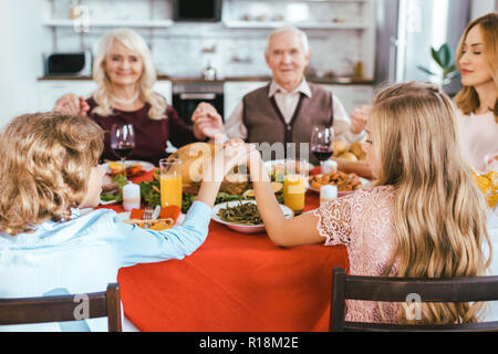 Bella famiglia felice pregare prima di cena di ringraziamento Foto Stock