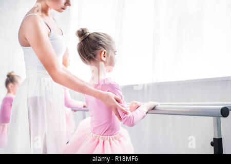 Ritagliato colpo di insegnante di danza esercitando con i bambini nella scuola di danza Foto Stock