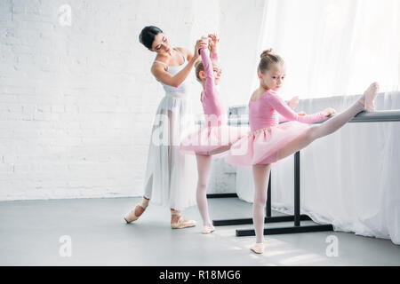 Bellissima giovane insegnante di danza esercitando con i bambini nella scuola di danza Foto Stock