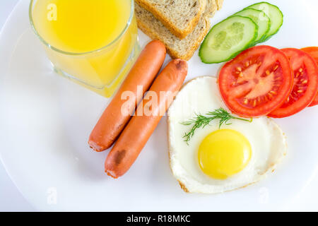 La colazione uovo fritto a forma di cuore, salsicce alla griglia, pane, verdura fresca, succo, vista dall'alto, sfondo bianco Foto Stock