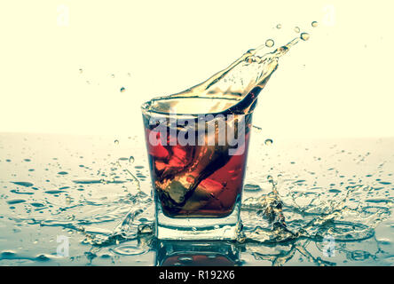 Spruzzi in vetro con soda, i cubetti di ghiaccio, sfondo bianco Foto Stock