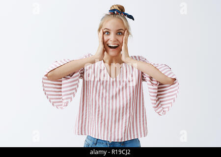 Non posso credere, stupito dalla sorpresa. Ritratto di lieta e senza parole felice femmina con capelli biondi in striping camicetta alla moda, tenendo le palme sul livello di che Foto Stock