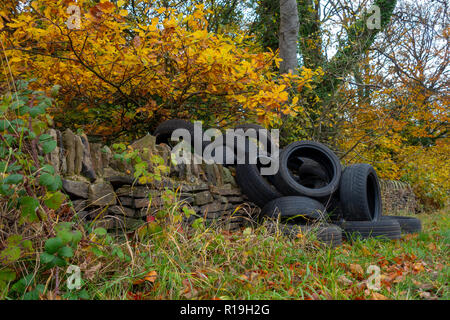 Un mucchio di auto usate di pneumatici oggetto di dumping sul lato di un grazioso vicolo del paese in collina eremita, Wortley, Sheffield, Regno Unito Foto Stock