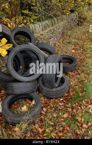 Un mucchio di auto usate di pneumatici oggetto di dumping sul lato di un grazioso vicolo del paese in collina eremita, Wortley, Sheffield, Regno Unito Foto Stock