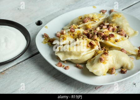 Cucina polacca tradizionale - deliziosi gnocchi caserecci, guarnita con fritto di cipolla e pancetta affumicata Foto Stock