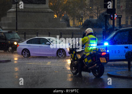 La polizia motociclista officer in heavy rain in Trafalgar Square e fermare il traffico. Londra, Regno Unito Foto Stock