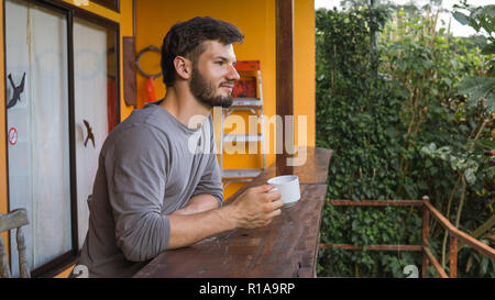 Uomo europeo godendo di tazza di caffè in un luogo tropicale Foto Stock