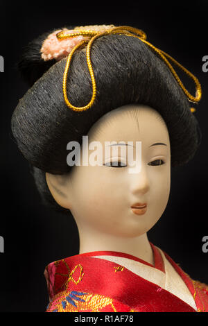 Giapponese Geisha bambola in rosso kimono isolati su sfondo nero Foto Stock
