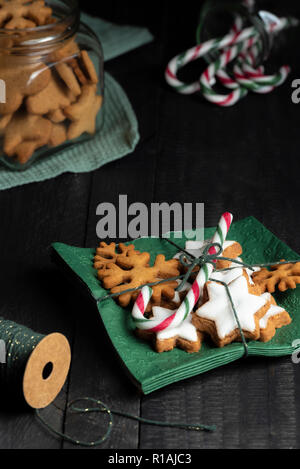 Chiudere l'immagine con diverse forme di gingerbread cookie e rosso-verde listati candy cane su tovaglioli con i cookie e lollipop in vasi in bac Foto Stock