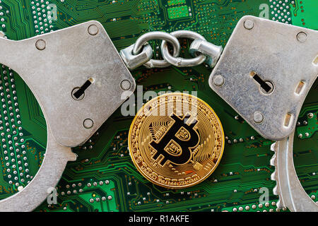 Bitcoin e manette sul chip di computer, vista dall'alto. Concetto di divieto di mining Foto Stock