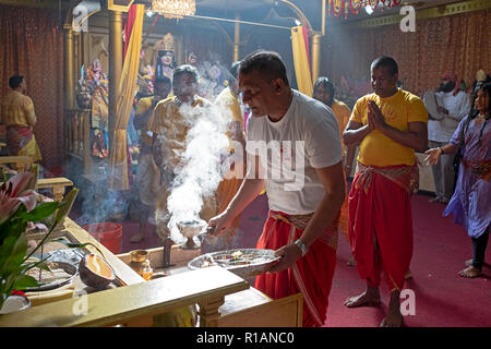 Un indù devoto brucia incenso davanti della dea Kali a Shakti tempio indù nel Queens, a New York City. Foto Stock