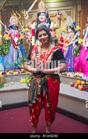 PANDITA. Ritratto di un bel sacerdote Indù nella parte anteriore di statue di divinità in un tempio nel Queens, a New York City. Foto Stock