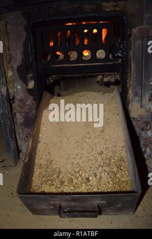 Close up di mattonelle di lignite sul fuoco con rosso giallo dentro le fiamme di un solido speciale forno, rosso e arancione texture sfocate su uno sfondo nero. Foto Stock